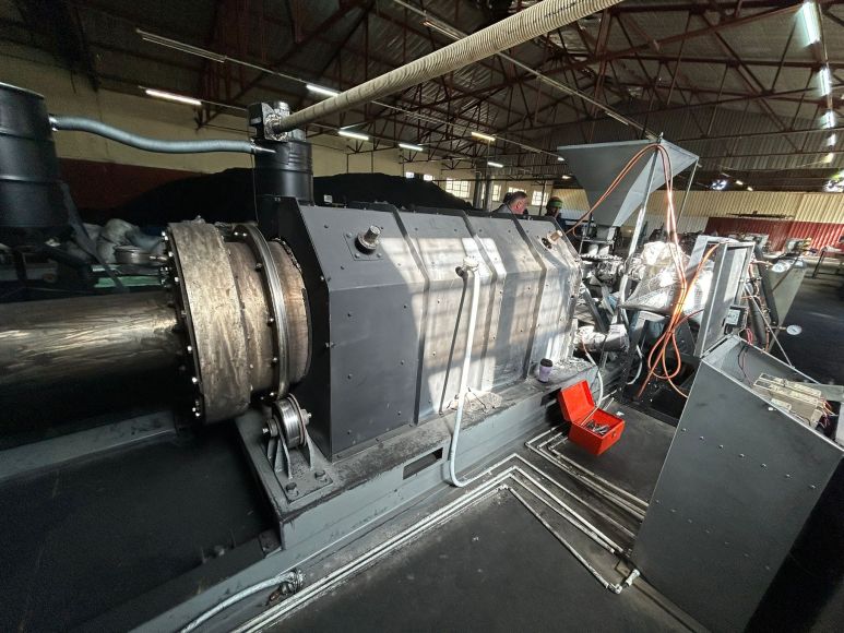 The Tenova Energy pyrolysis reactor — a horizontal rotary kiln with drive assembly inside an industrial building.